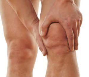 Person holding their knee due to pain